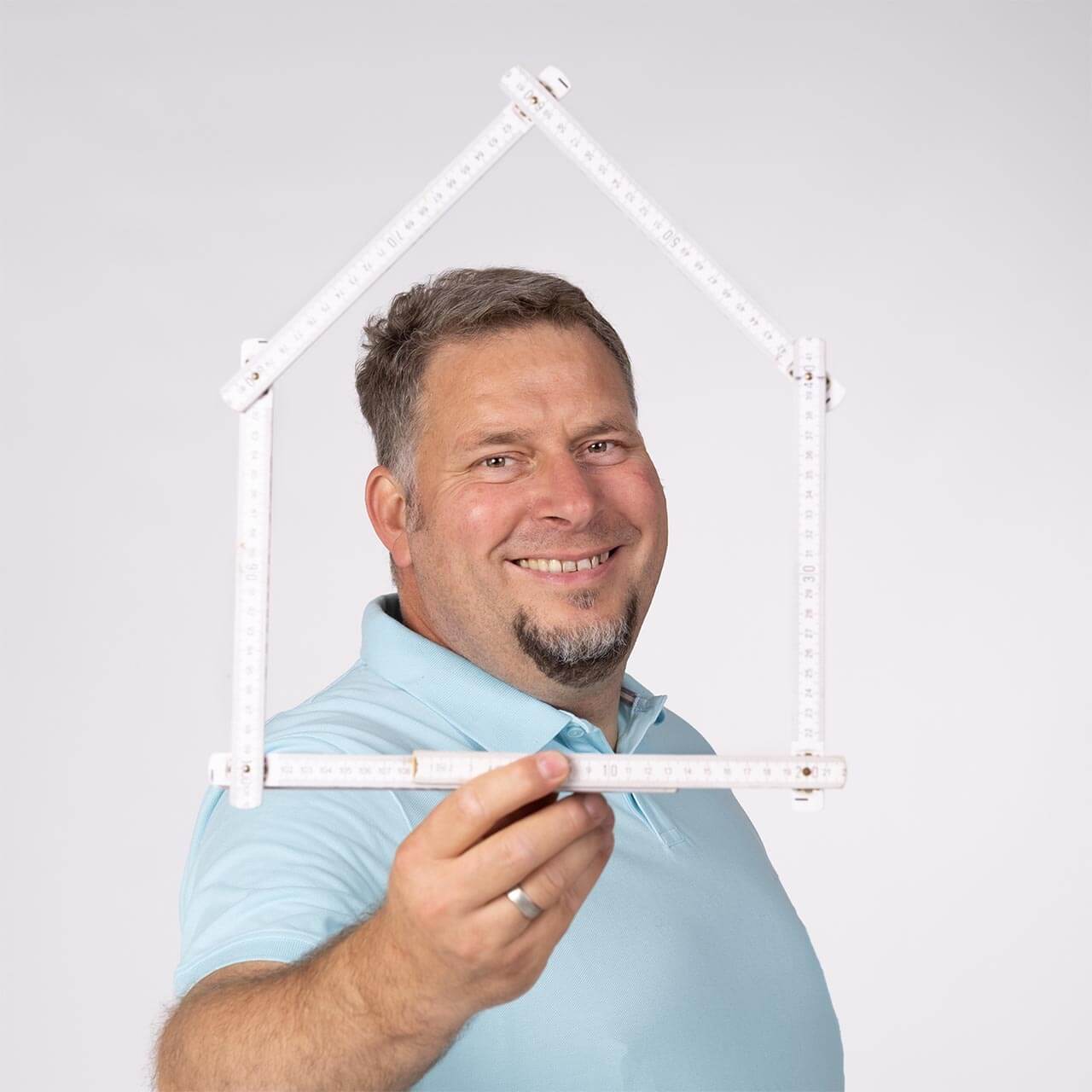 Porträt Matthias Klein mit Zollstock, der ein Haus formt